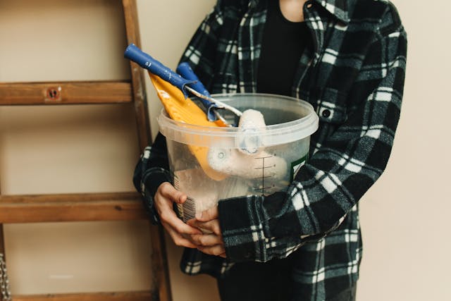 a person holding a bucket of paint supplies