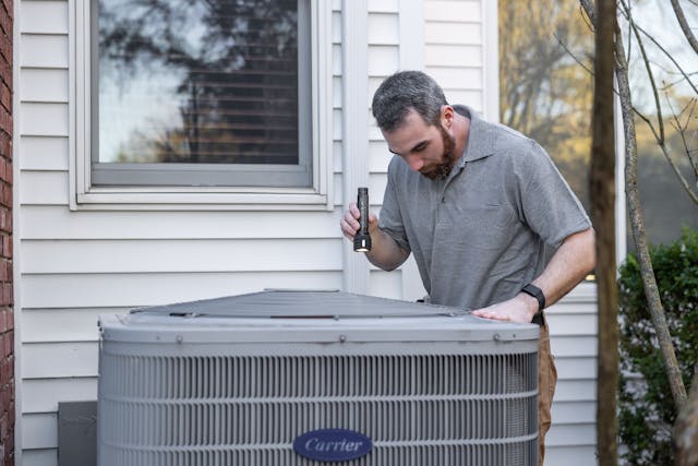 a person inspecting an air conditioning unit